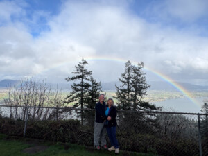 Brad and Maren standing under a rainbow in Oregon after the long trip home from Costa Rica
