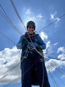 Looking up at a pilot from inside the lines of a paraglider.