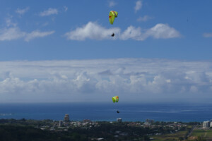 Two paragliders flying in opposite directions with Jaco in the distance.