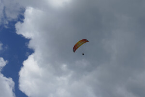 Paraglider above launch and below a cloud.