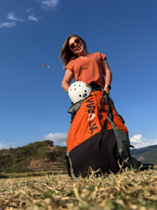 Paraglider Pilot after landing with a paraglider in the air above her right shoulder