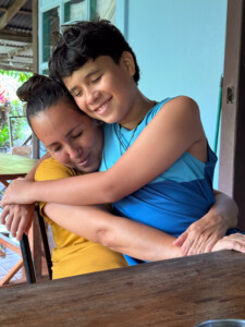 Mariana with her son sitting on her lap, sharing a family moment, with both looking adorable.