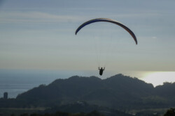 Flying into the light. Paraglider pilot enjoying an afternoon flight.